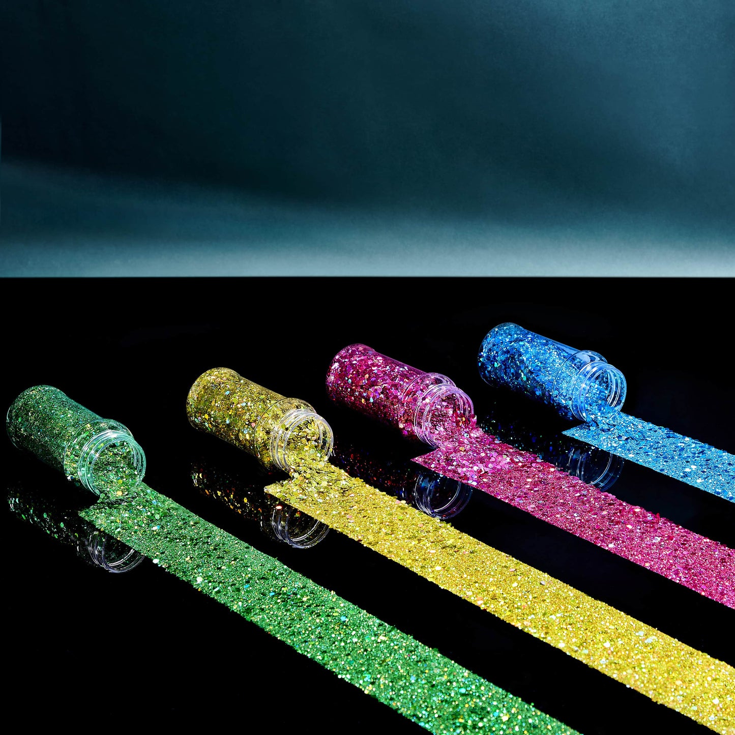 Four glittery sticks in green, gold, pink, and blue on a reflective surface with a dark background.
