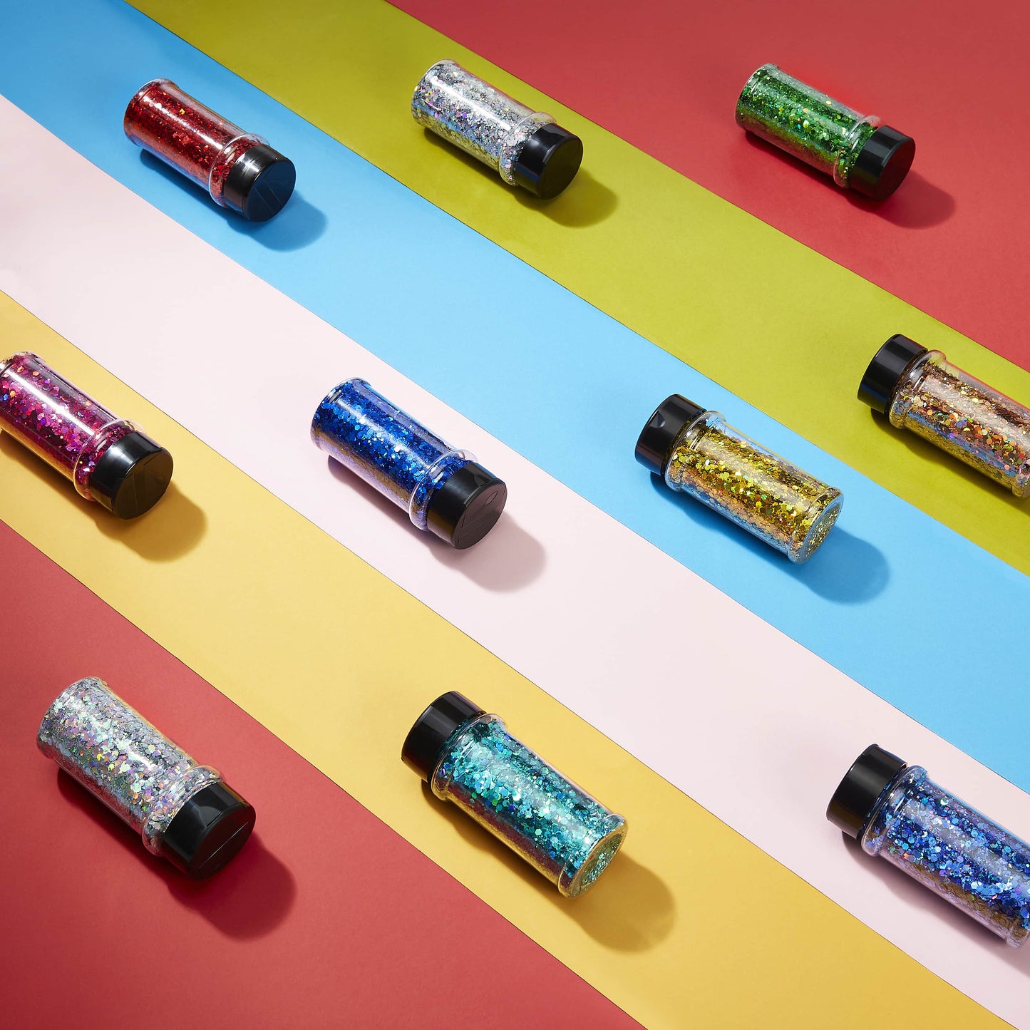 Colorful glitter jars on a multicolored striped background