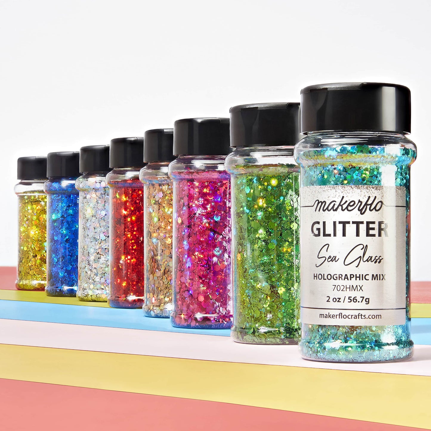 Row of glitter jars with colorful contents on a white background