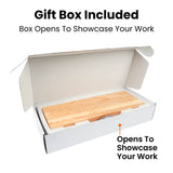 A white cardboard gift box shown open on a white background, with a light wood board or tray inside. Text above and below reads 'Gift-Ready Wow-Ready' and 'Box Opens To Showcase Your Work,' with an orange pointer line to the bottom text.